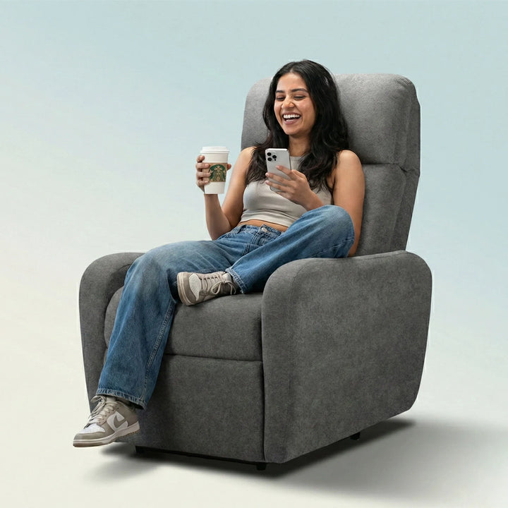 Woman relaxing on Hush Hiven EVA manual recliner chair dark grey single seater enjoying coffee while using smartphone at home