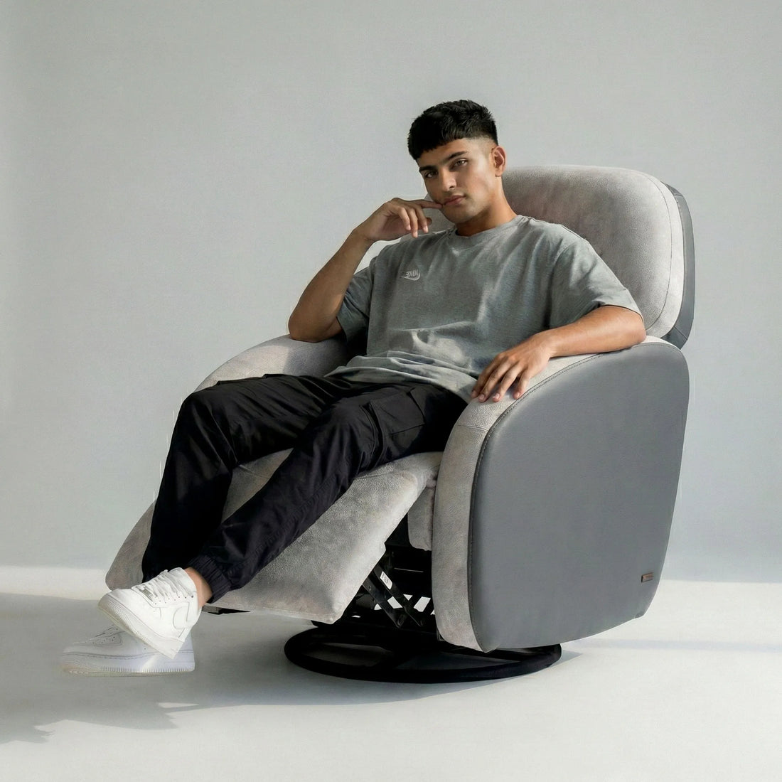 Man relaxing on Hush Hiven Pebble motorized recliner chair grey dual tone boucle leatherette with footrest