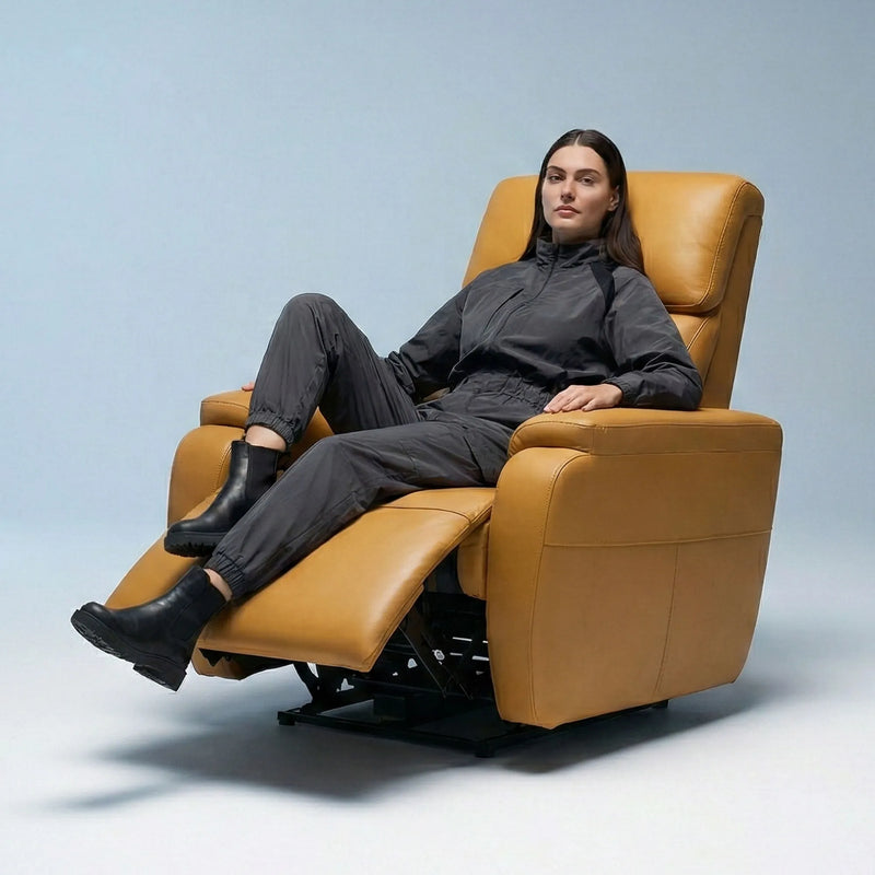 Woman relaxing on Hush Hiven Zeus tan motorized leatherette recliner chair with extended footrest in studio setup